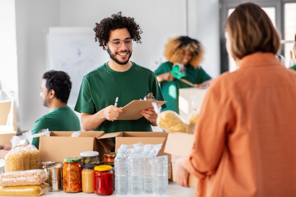 Volunteer packing food in box wearing green shirt and glasses, smiling