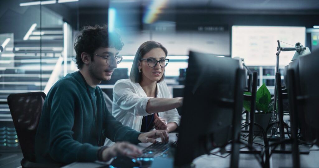 Two professional colleagues wearing glasses looking at computer screen