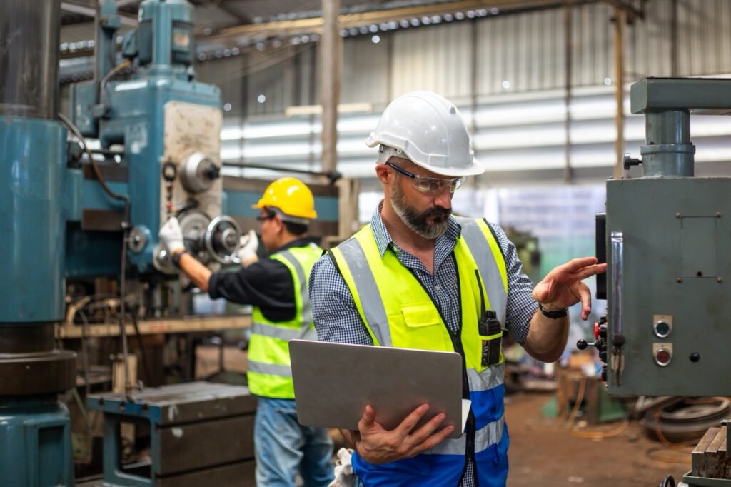 Manufacturers and engineers holding computer reviewing technology