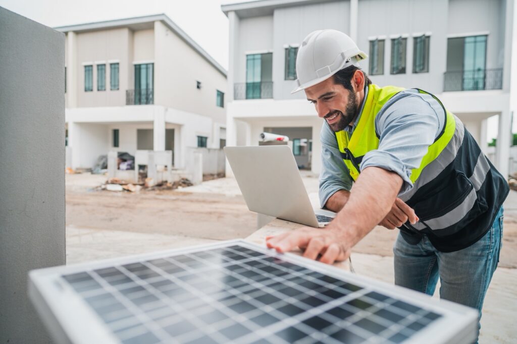 Construction worker wearing best and hardhat looking at laptop screen