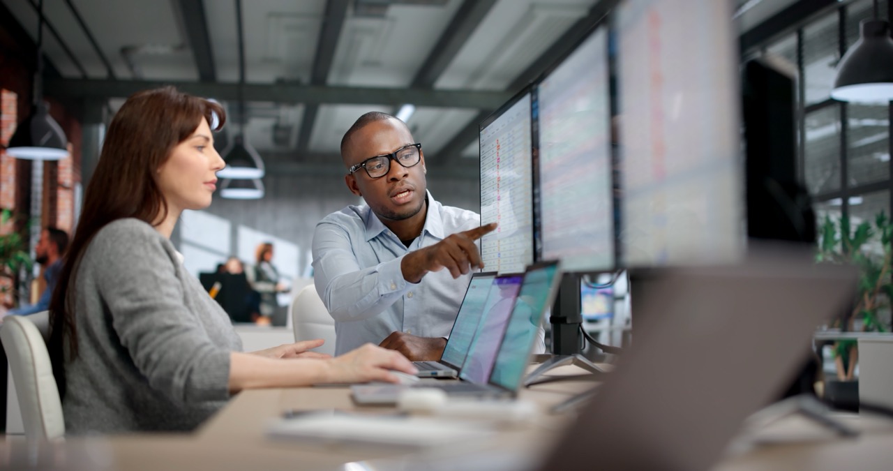 one male and one female professional working together, looking at computer screen